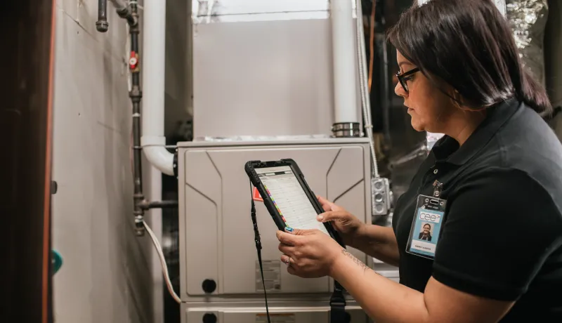an energy auditor working in a basement on an iPad