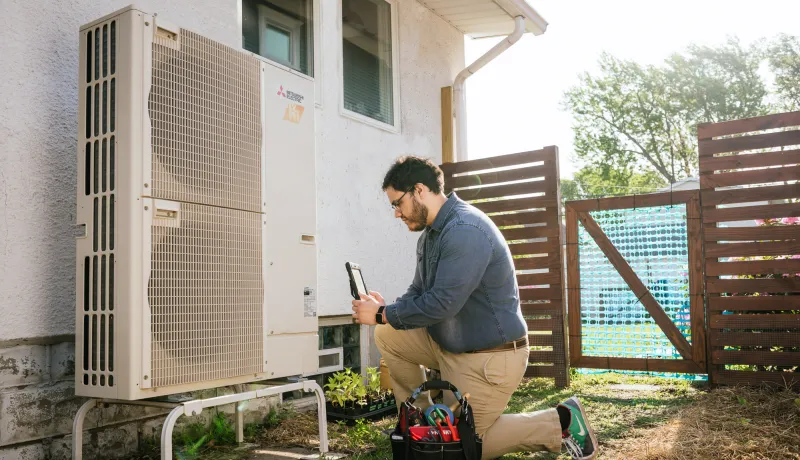 A person inspects a heat pump.