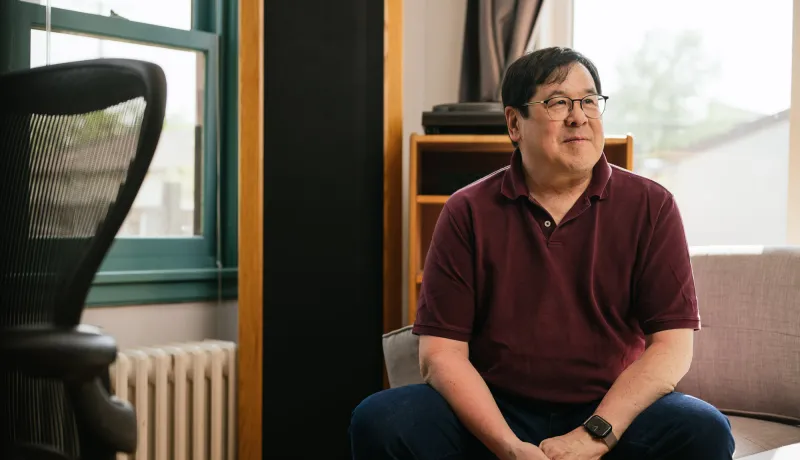 Lester sits in his home, which is heated and cooled with a cold climate air source heat pump.