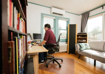 A person sits at their desk with a mini-split system behind them.