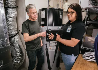 two people taking a look at an iPad in a basement beside a water heater