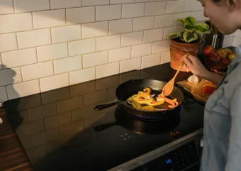 A person stirs food on their induction stove.