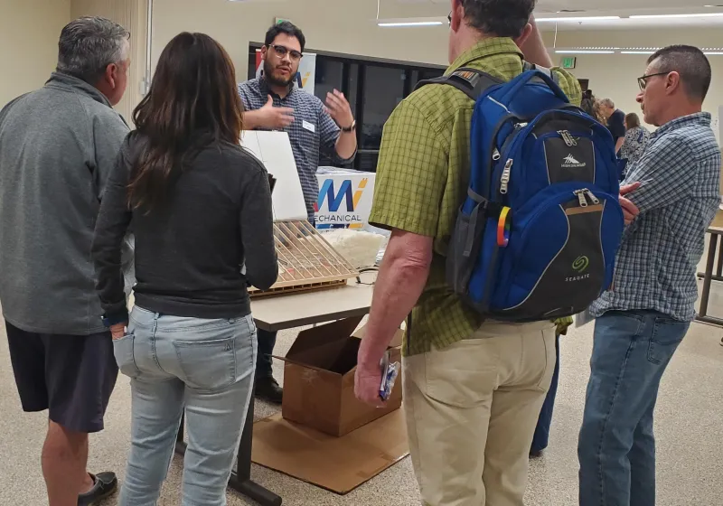 A CEE employee speaks to several residents at an event.