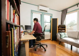 A person sits at their desk with a mini-split system behind them.