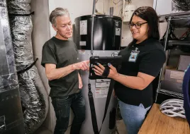 two people taking a look at an iPad in a basement beside a water heater